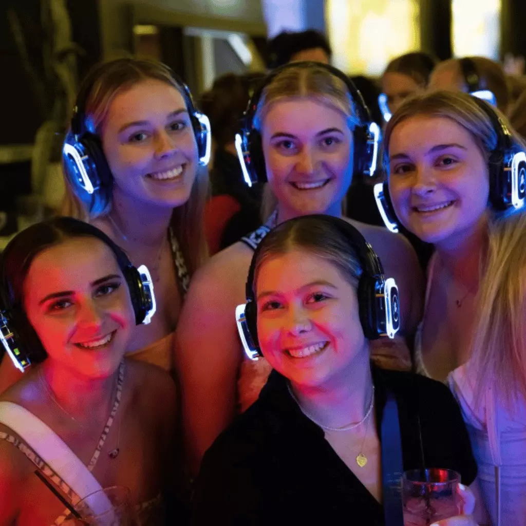 Group of friends wearing silent disco headsets and smiling at the camera