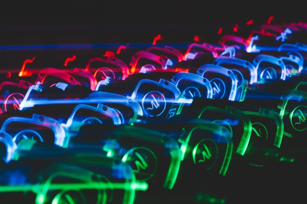 Music By Design branded headsets in pink, blue and green all lined up in 3 rows