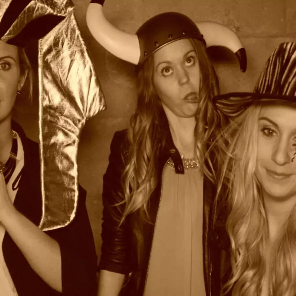 Group of friends in the photobooth wearing funny accessories